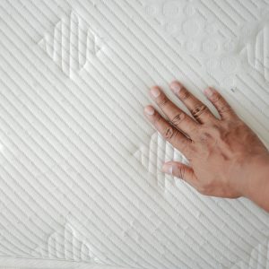 Hand raakt matras van koudschuim aan