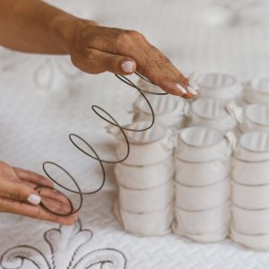 Hand houdt metalen onderdeel dat in matras zat vast