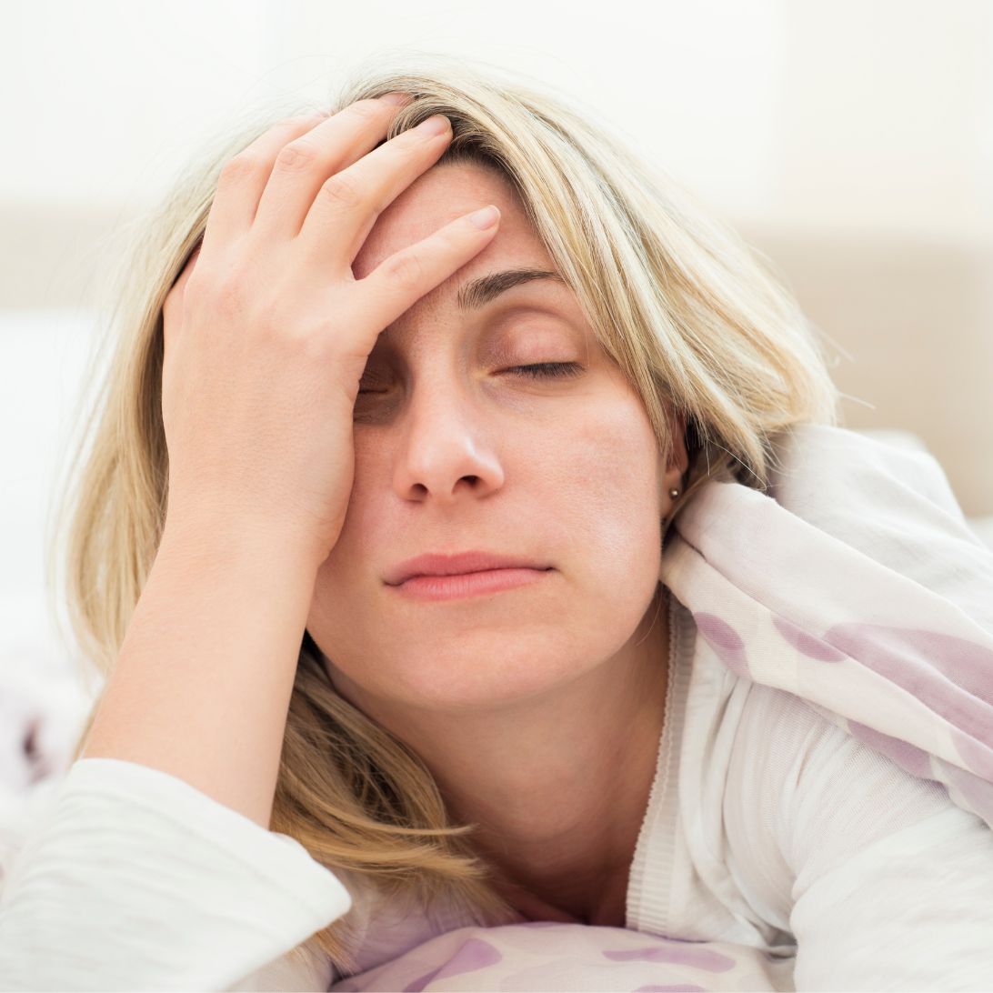 Vrouw heeft last van slaapproblemen en ligt wakker, heeft hand op haar hoofd