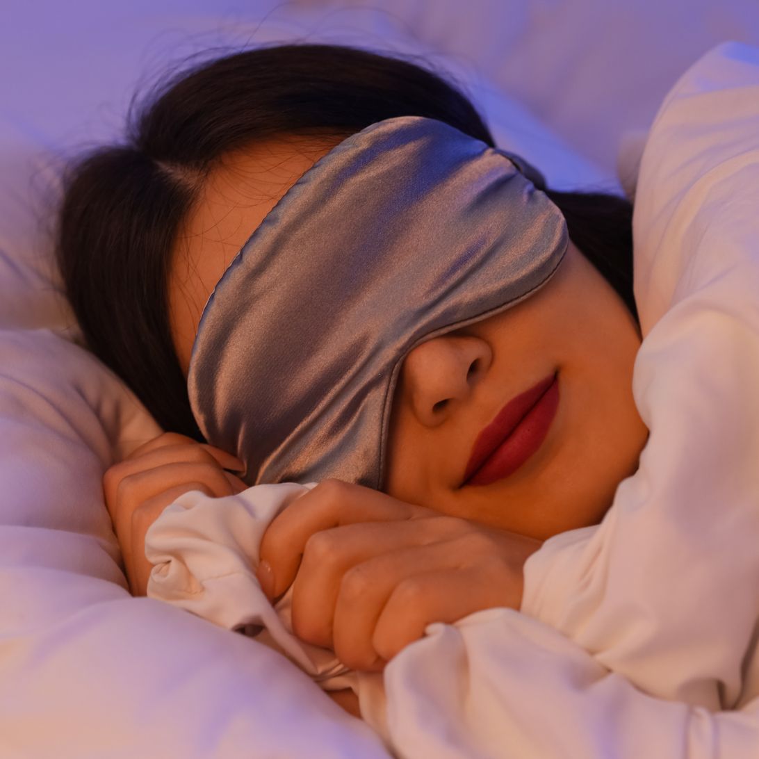 Vrouw ligt heerlijk te slapen tijdens koude nachten dankzij warm dekbed en slaapmasker