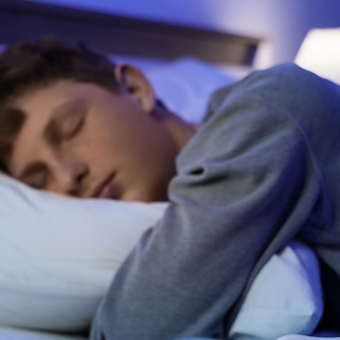 Tiener ligt in bed te slapen