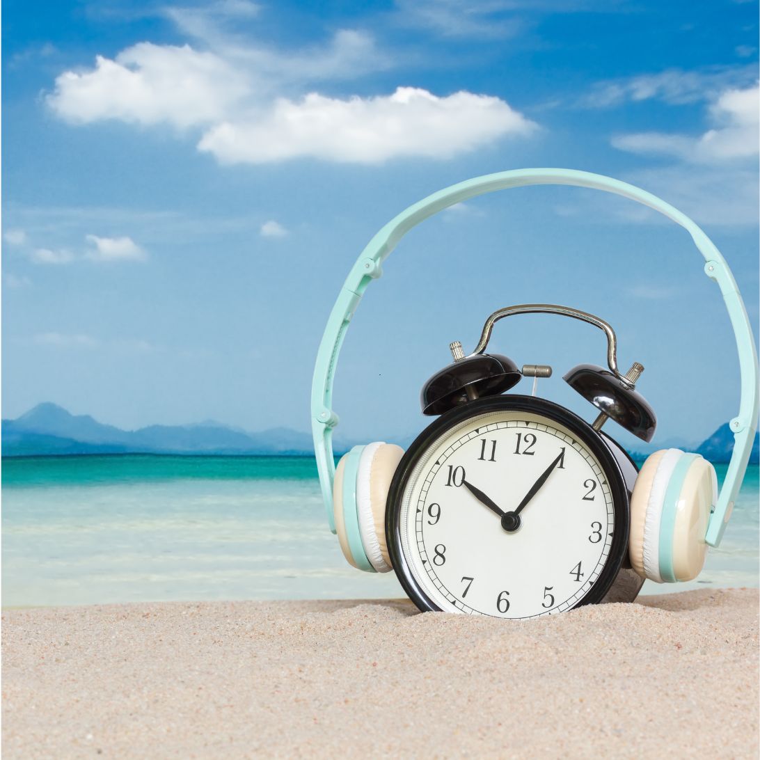 Klok met koptelefoon op het strand, symbool voor zomertijd