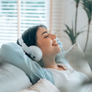 Vrouw ligt in bed met koptelefoon op naar ASMR te luisteren