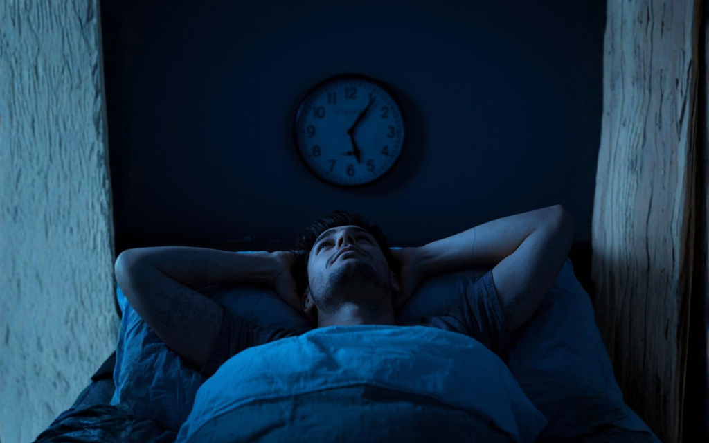 Man ligt met zijn ogen open in bed