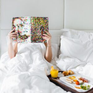 Vrouw is tijdschrift aan het lezen en in bed aan het eten voor het slapengaan
