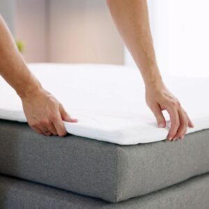 Persoon legt topper op boxspring