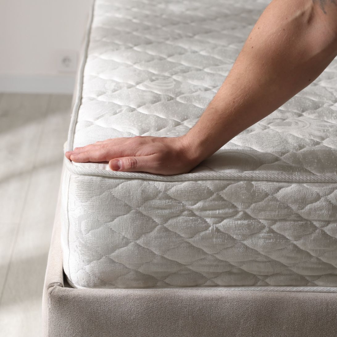 Vrouw test hardheid matras tijdens nieuw matras kopen
