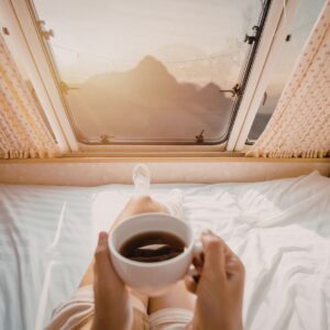 Persoon drinkt kopje koffie op matras van Seminautic in camper