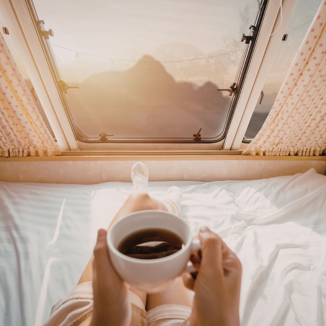 Persoon drinkt kopje koffie op matras van Seminautic in camper