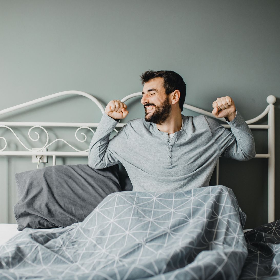 Man rekt zich tevreden uit na een nacht op een matras van Slaaptevreden Oosterhout
